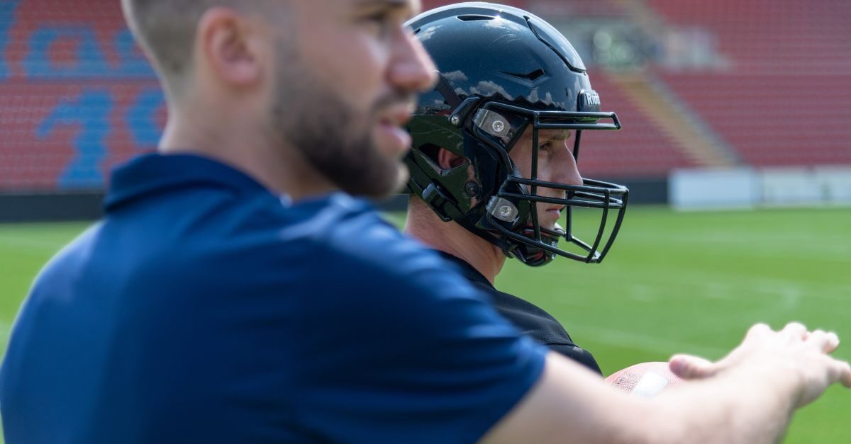 A football coach equips an American football player with a player tracking device.