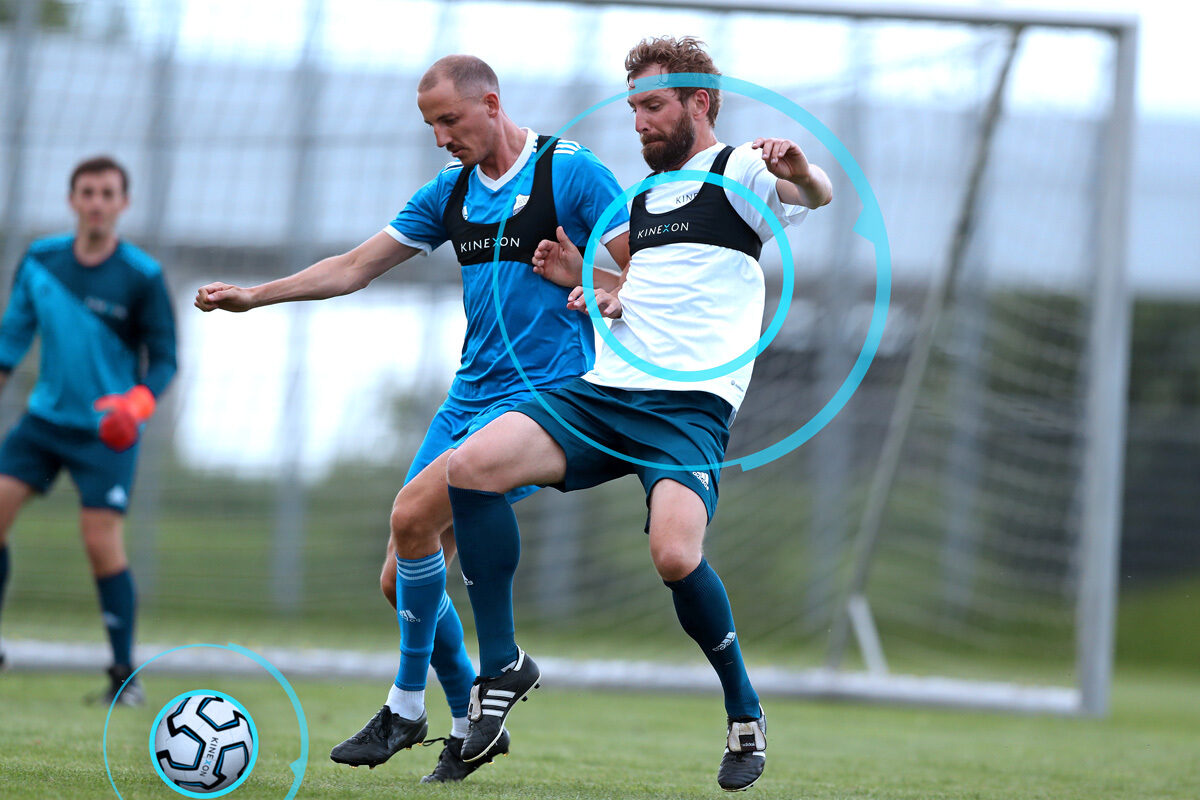 Footballers playing with a soccer ball with an integrated chip or ball tracker that provides information for coaches and referees.