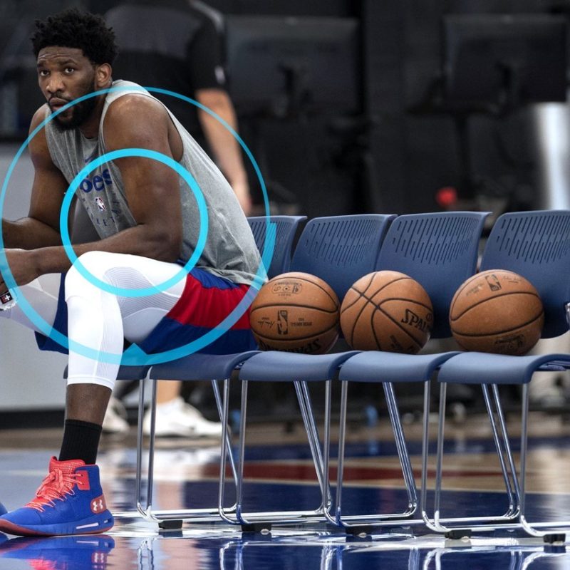 Basketball Player sits on bench beside balls